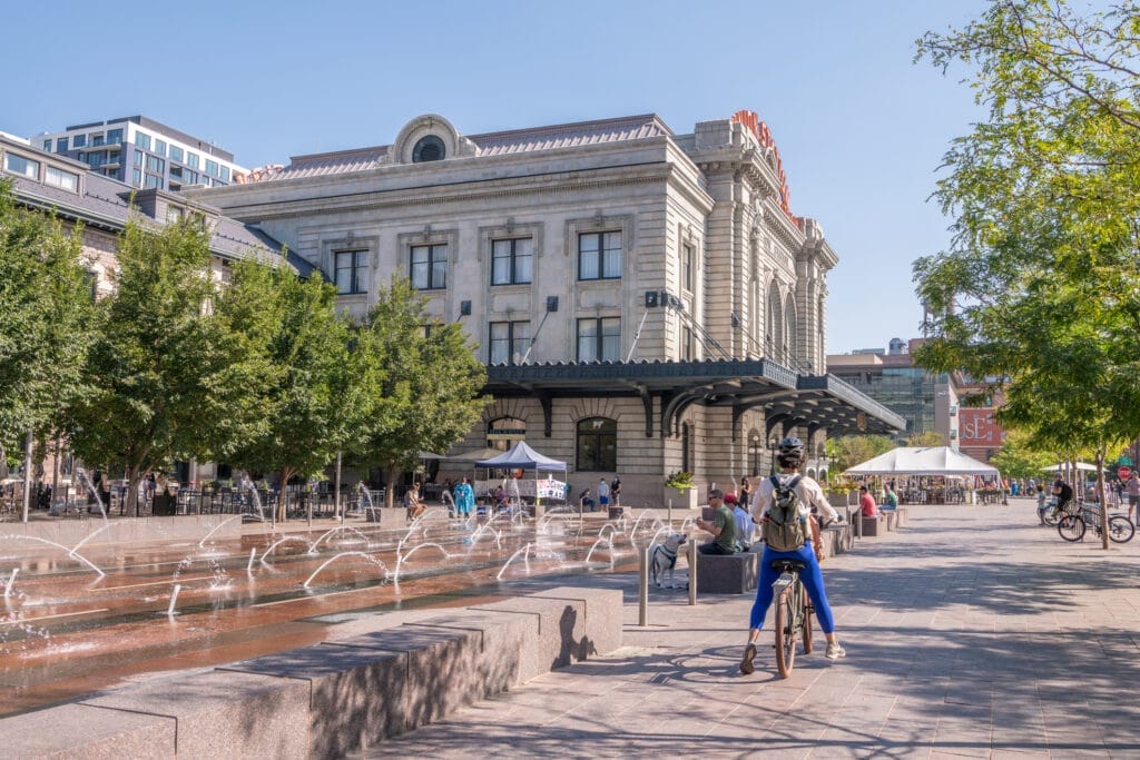 Denver, Colorado - August 28, 2021: A woman rides a bicycle in the plaza at Union Station, downtown, in the LoDo (Lower Downtown) neighborhood.