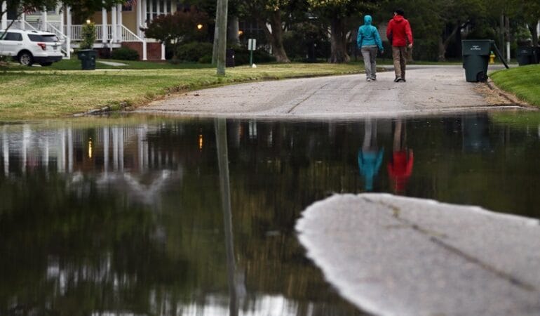 Two people walk on a flooded road