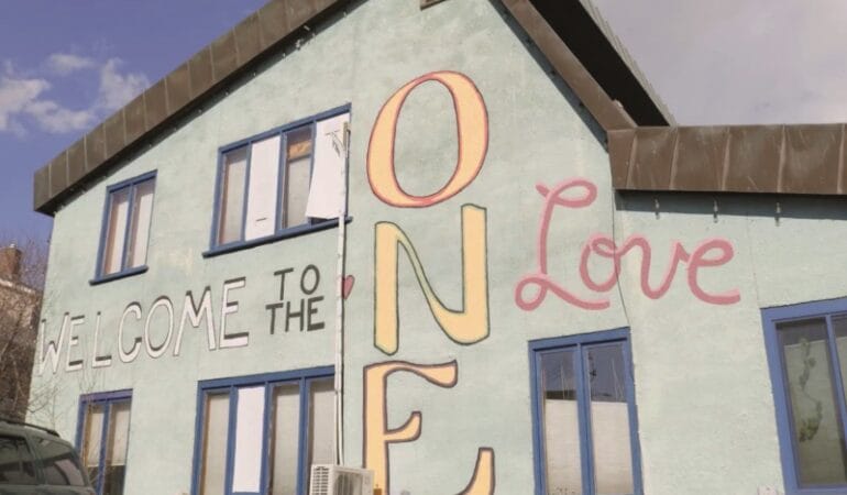 A building painted with the phrase 'Welcome to the ONE Love'