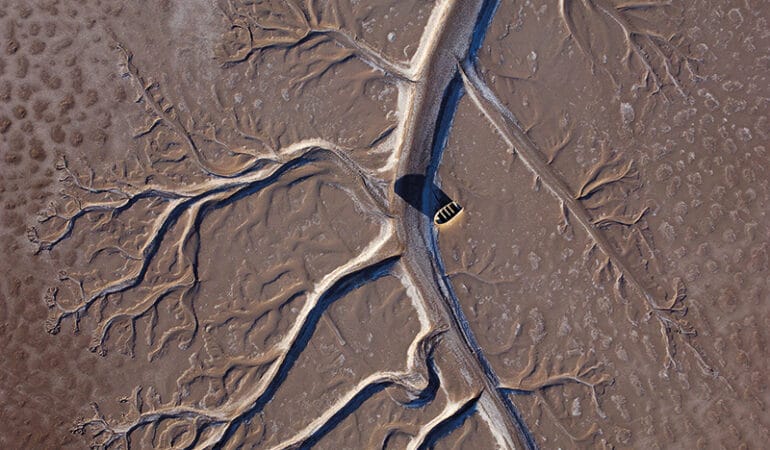 Aerial view of a fishing boat stranded on a brown and dried up Colorado River Delta.