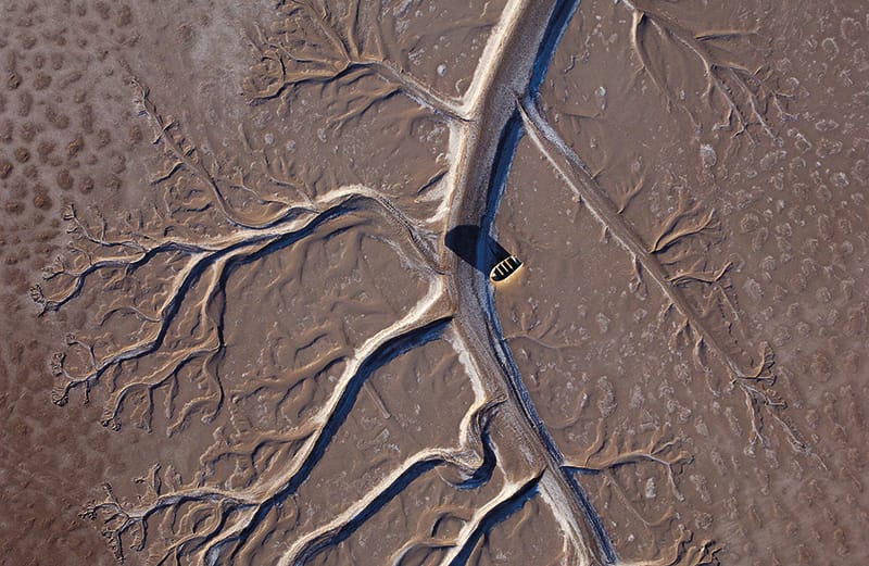 Aerial view of a fishing boat stranded on a brown and dried up Colorado River Delta.