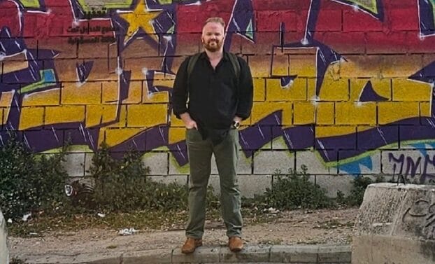 A man stands in front of a graffiti-covered wall
