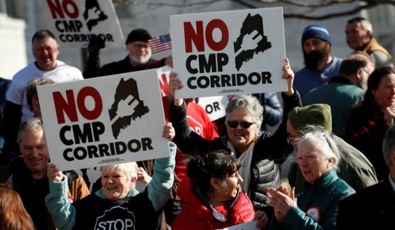 Los manifestantes sostienen carteles que se oponen a un corredor hidroeléctrico planificado en Maine