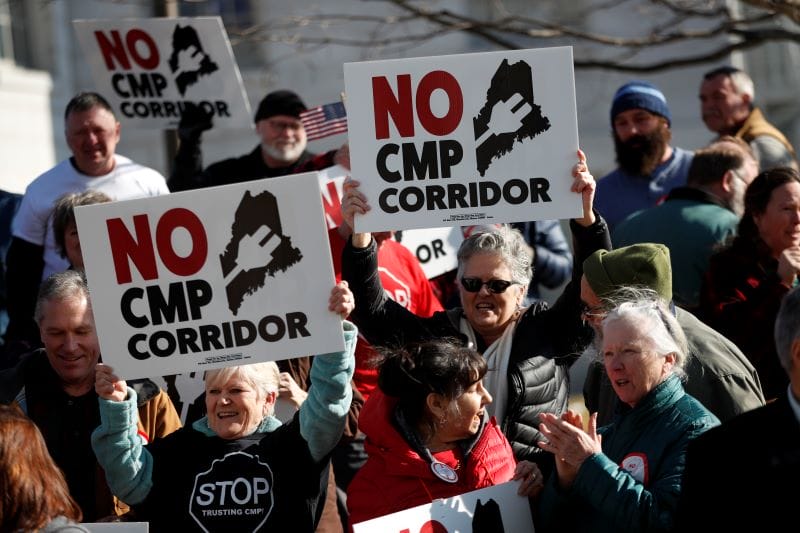 Los manifestantes sostienen carteles que se oponen a un corredor hidroeléctrico planificado en Maine