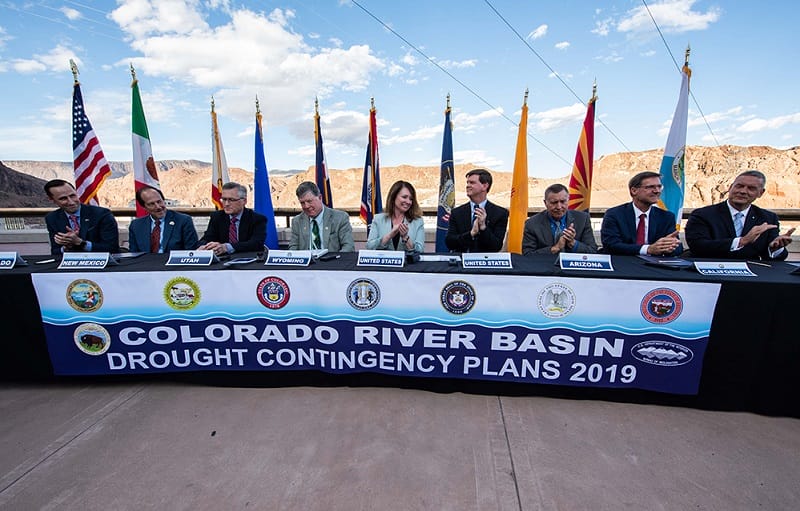 Federal and state officials sit at a table to celebrate the signing of the Colorado River drought contingency plan atop the Hoover Dam