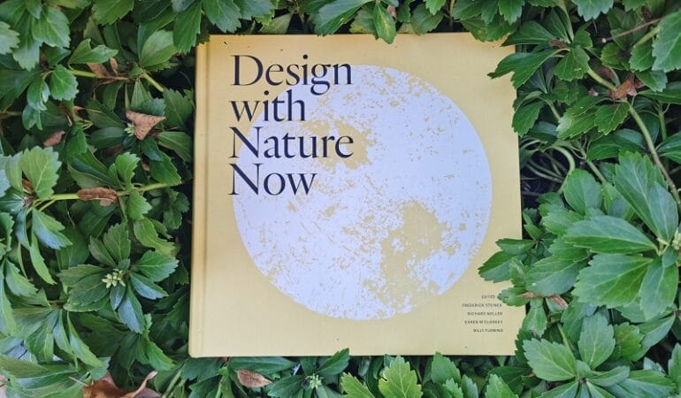An image of the book Design with Nature Now surrounded by leaves.