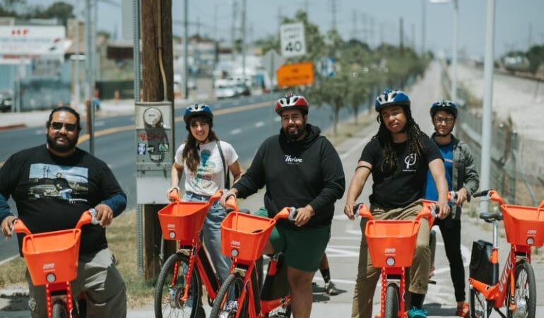 A group of people posing with orange e-bikes