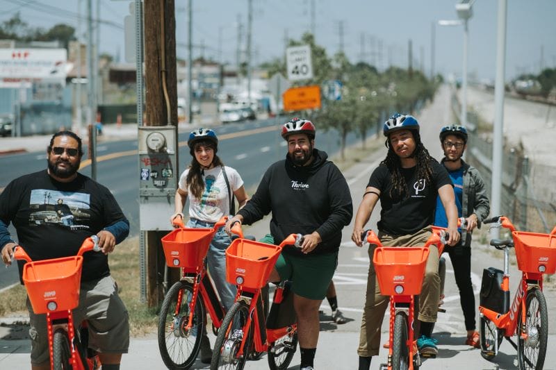 A group of people posing with orange e-bikes
