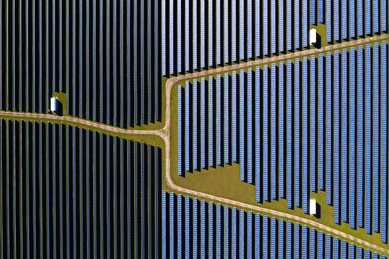 Dark blue vertical lines of solar panels seen from directly above fill a little more than a third of the left side of the image