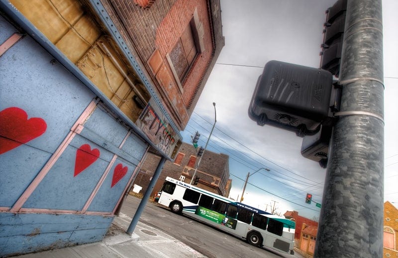 Photograph shows the side of a blighted building on a city street with crumbling paint