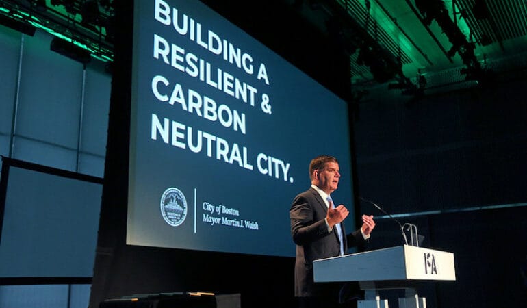Boston Mayor Martin Walsh stands against the backdrop of a powerpoint presentation at a podium speaking to a crowd at the annual Greenovate Awards.