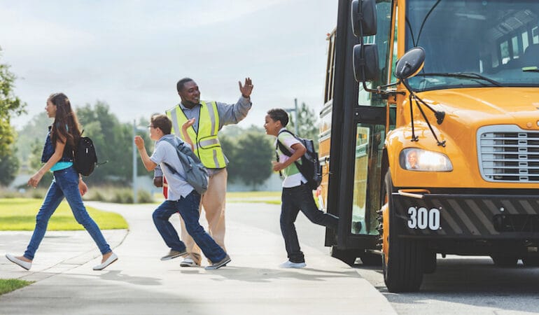 Image: Children departing a yellow school bus.