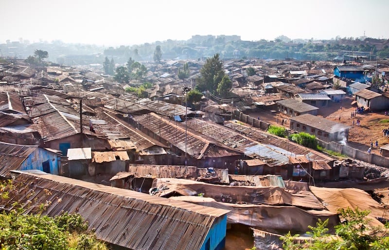 Shacks with corregated metal roofs are crowded together in most of the foreground