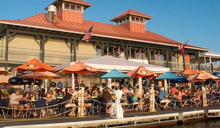A waterfront restaurant with an outdoor patio full of diners.