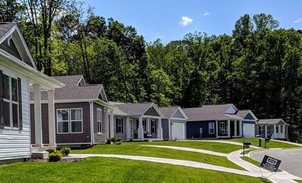 A row of homes, green lawns and a neighborhood sidewalk.