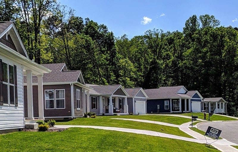 A row of homes, green lawns and a neighborhood sidewalk.