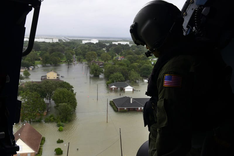 A man looks at a flooded area from a helicopter