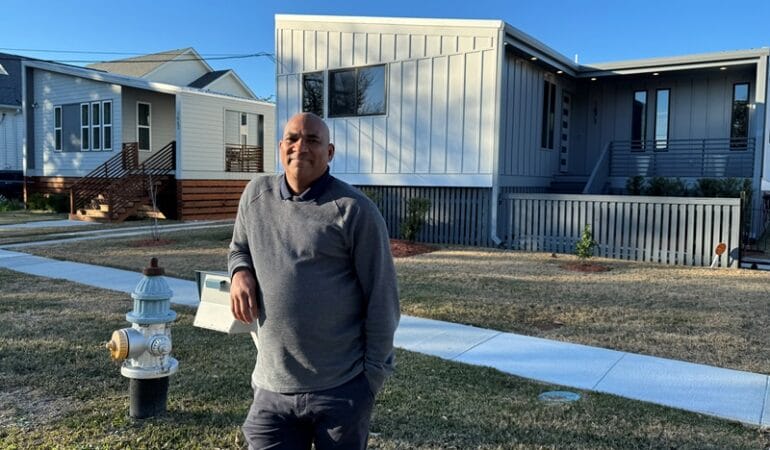 Oji Alexander, CEO of People's Housing+ in New Orleans and a former Fulcrum Fellow, in front of two People's Housing+ homes.