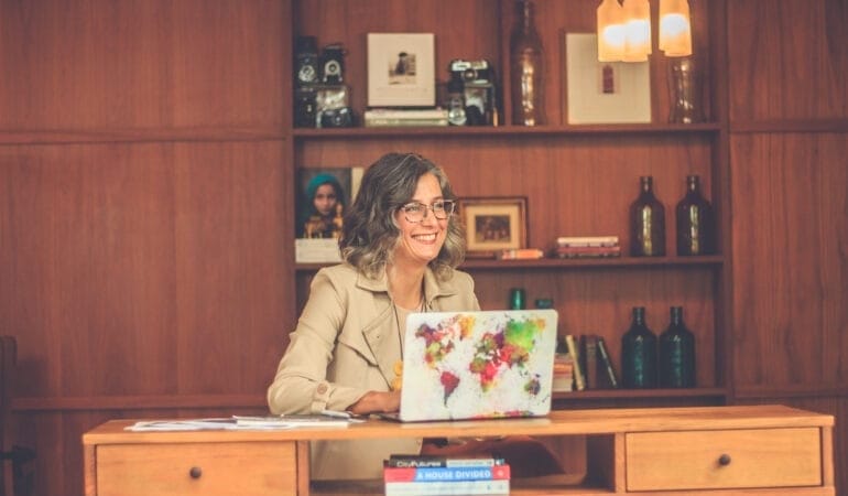 Anacláudia Rossbach sitting at a desk in front of a computer.