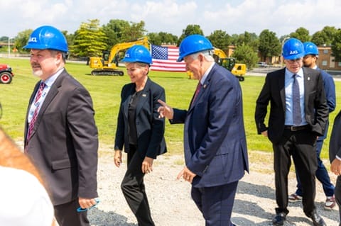 Photo of group of people walking while wearing blue hard hats.