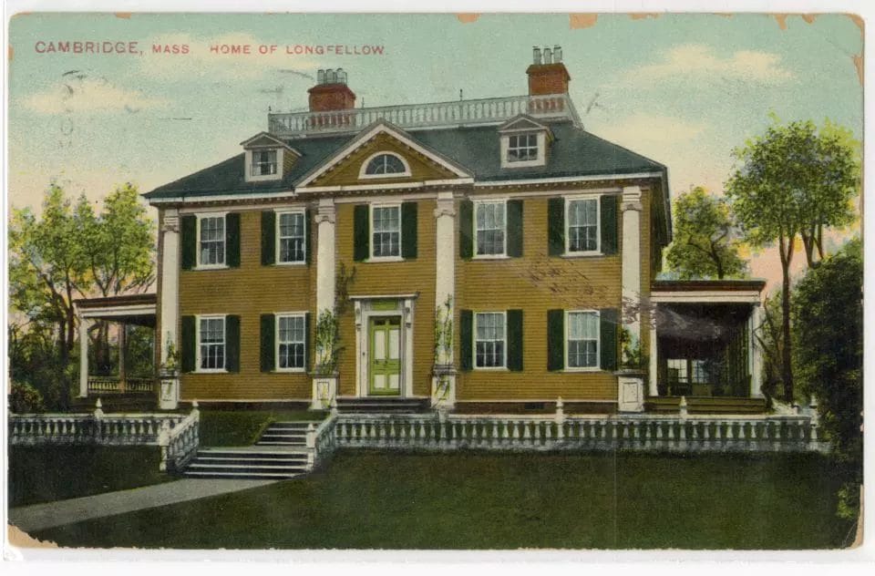 A colorized postcard shows the large, yellow Colonial Revival house that Henry Wadsworth Longfellow lived in. The house has white trim, dark shutters, and two chimneys.