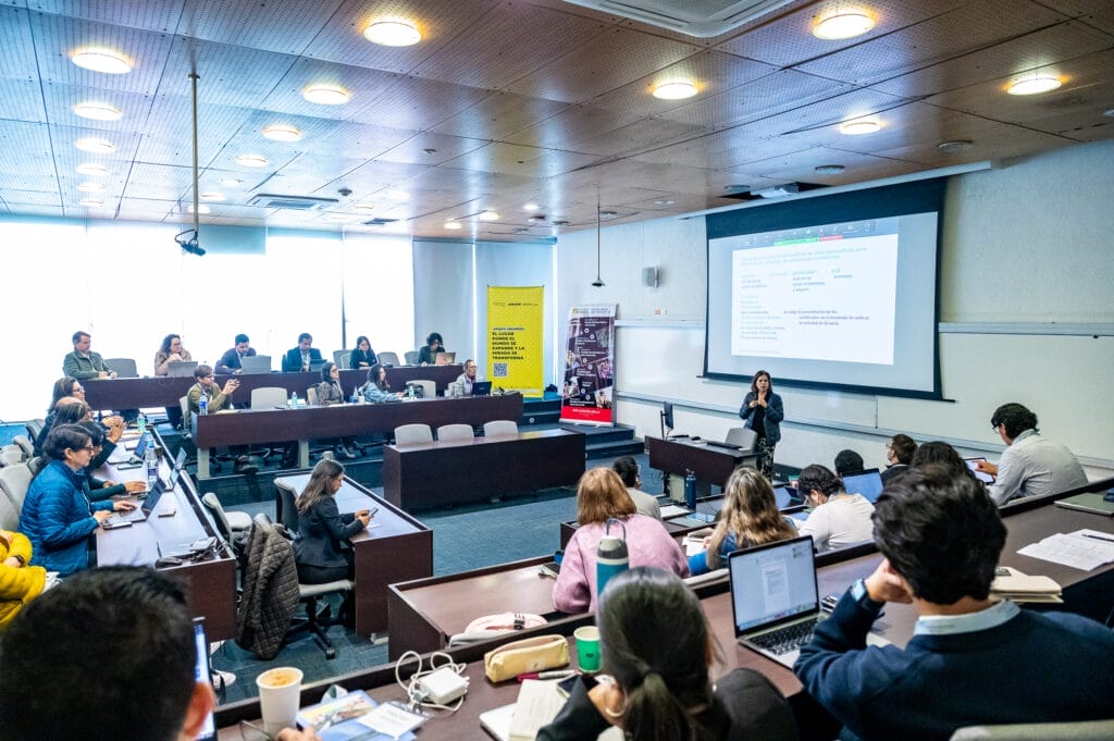 Un salón de clases donde los participantes del curso prestan atención a la presentadora.
