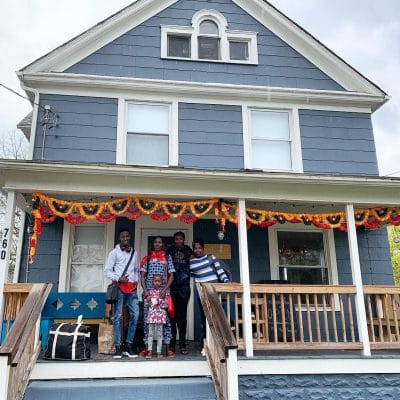 This image shows a family standing on the porch of the Exchange House.  