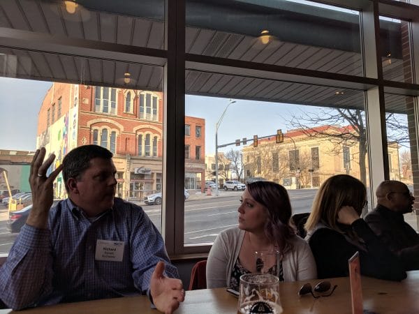Two community of practice participants enageg in a discussion at a table at the Akronym Brewing Company.